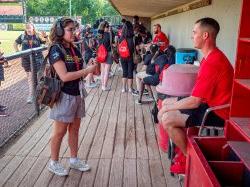 一名学生在休息区采访一名棒球运动员.