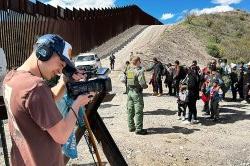 一名学生带着耳机和相机拍摄墨西哥和亚利桑那州边境的场景.