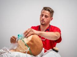 Male Nursing student observing as a mask is placed on a manikin.