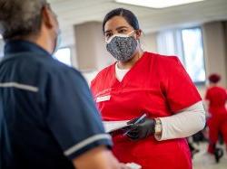 戴着防护口罩和手套的护理系学生与注意力不集中的病人交谈.
