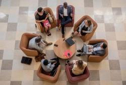 Graduate students collaborating while seated in a circle with laptops and papers